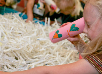 A girl is looking through a bail of hay made out of shredded paper. She is looking for lost coins.