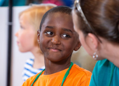 An elementary-aged boy smirks at his small group leader as he recites his memorized scripture.