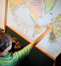 Children pointing on a map at different mission locations.