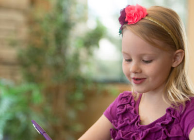 An elementary aged girl sitting at a table working on an easy craft.