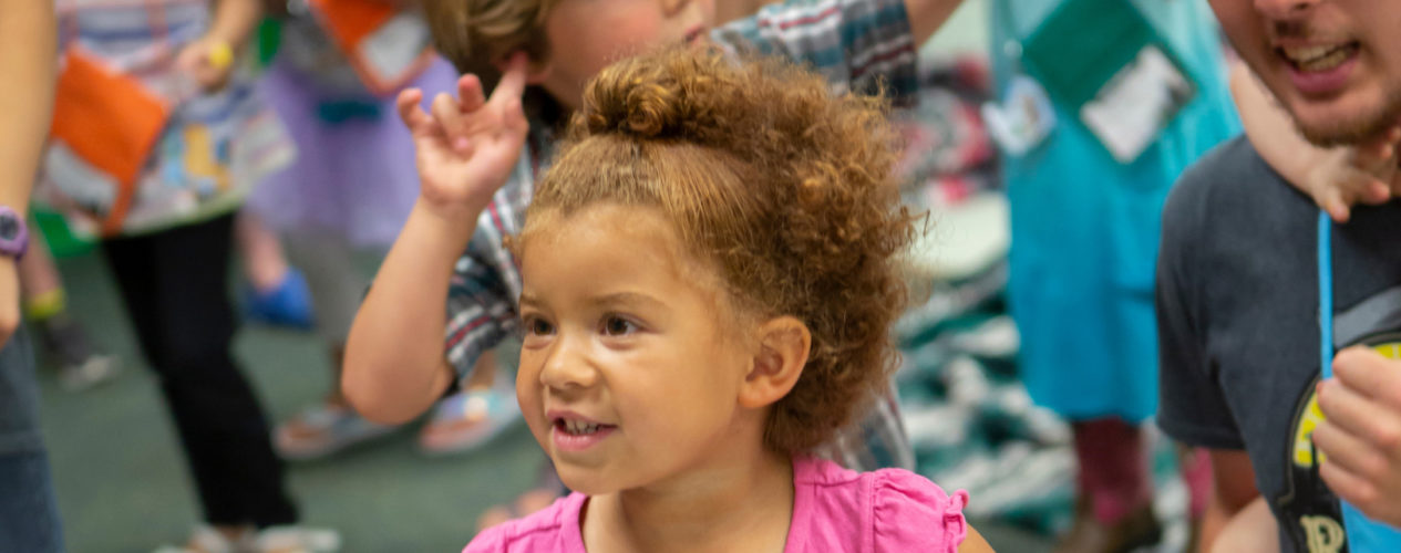 A toddler dances to music in her classroom.