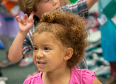 A toddler dances to music in her classroom.