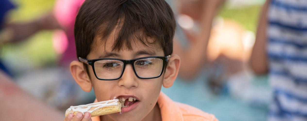 An elementary aged boy eats a snack in his children's ministry.