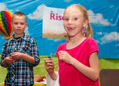 Two children looking excited as they stand in front of an Easter back drop.