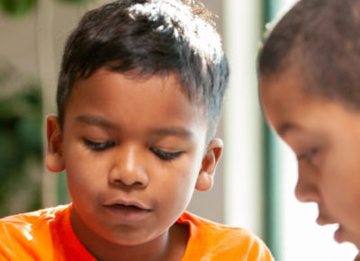 Two elementary boys concentrate hard as they participate in a craft.