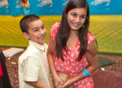 A preteen girl and boy laugh as they participate in a pinata.