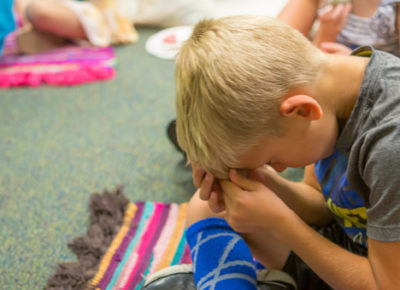 An elementary aged boy praying.