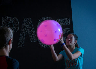A group of preteens playing indoor glow-in-the-dark dodgeball.