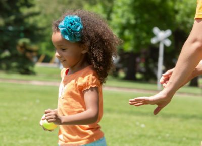 A preschool girl running outside while playing a Bible game.