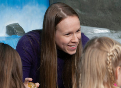 A female children's ministry volunteer is leading a small group of children.