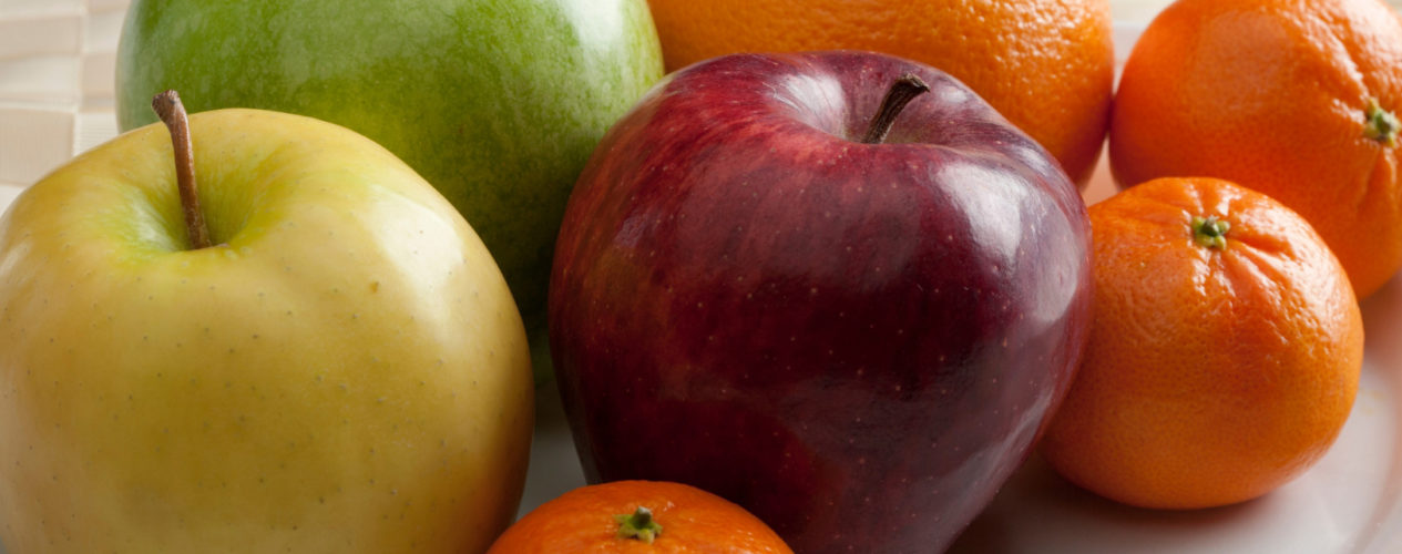 A table of fruit, including apples and oranges.