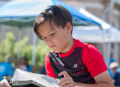 A boy is studying his Bible outside.