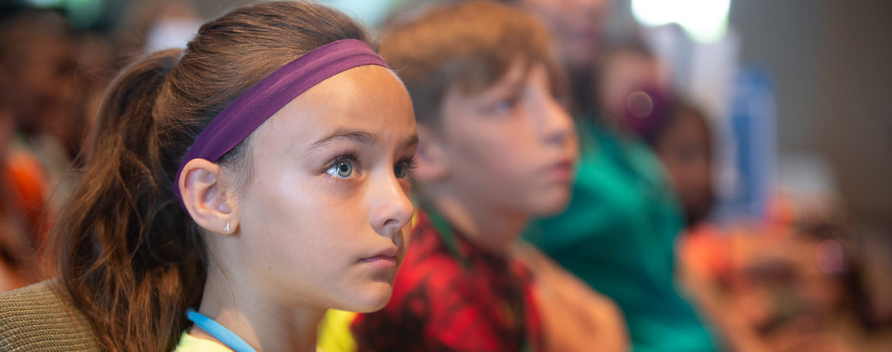 A serious looking preteen girl is listening to a message.