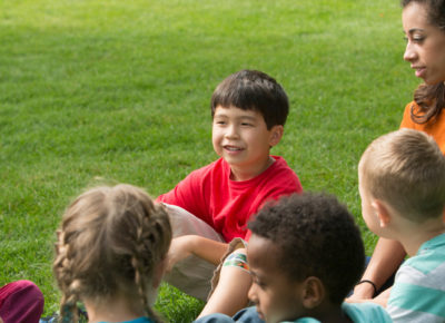 A group of preschoolers smile as they sit in a circle.