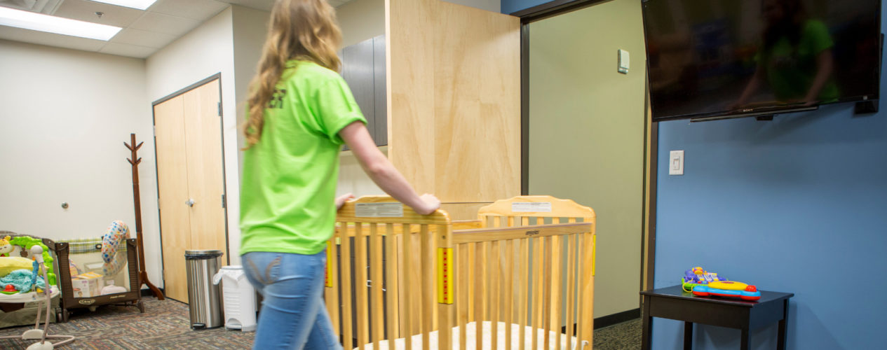 A woman pushes a crib out of the nursery.