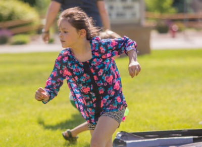 A preteen girl participates in a Bible racing game outside.