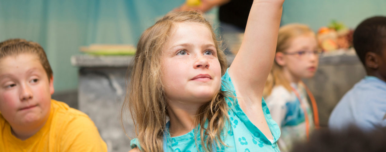An older elementary girl raises her hand during the Easter children's message.