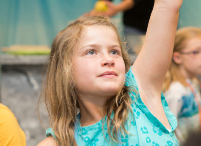 An older elementary girl raises her hand during the Easter children's message.