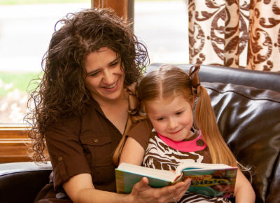 A mom is reading the Bible with her kindergarten daughter.