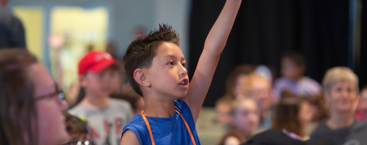 An elementary aged boy with special learning needs raises his hand.