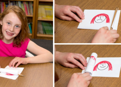 Little girl smiling at the camera as she colors. Two close up shots of what she's coloring include a smiling face and frowning face.