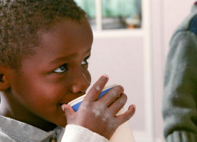 Elementary aged boy drinks from a water cup.