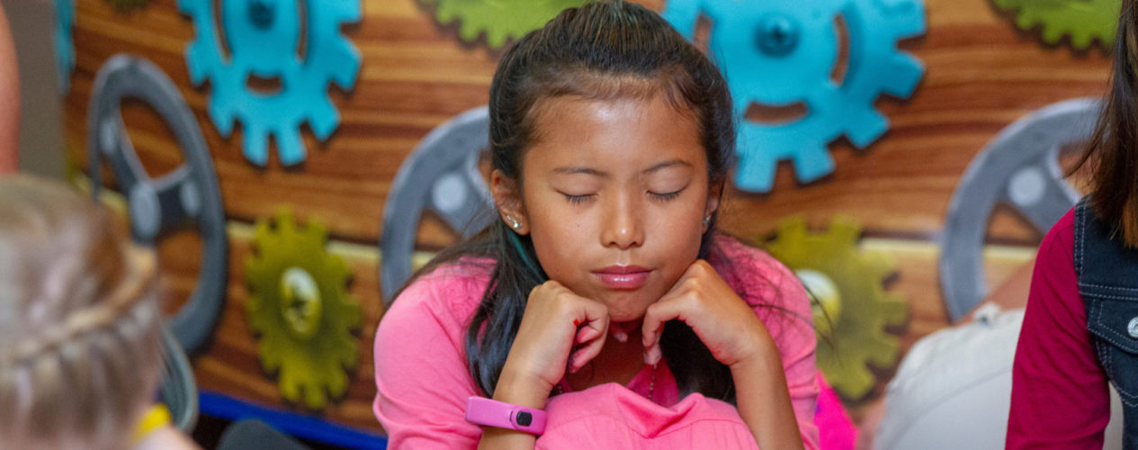 A preteen girl has her eyes closed in deep prayer.