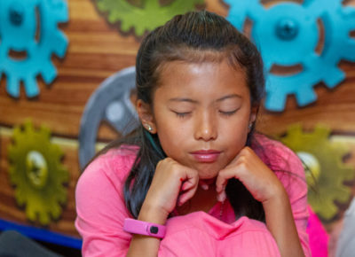 A preteen girl has her eyes closed in deep prayer.