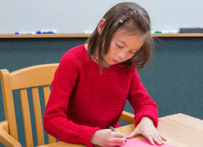 An elementary-aged girl participating in a Valentine craft.