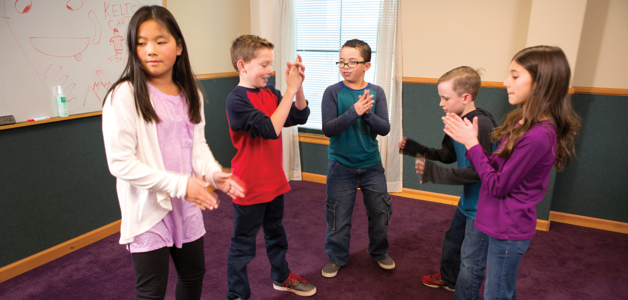 Children standing in a semi circle clapping.