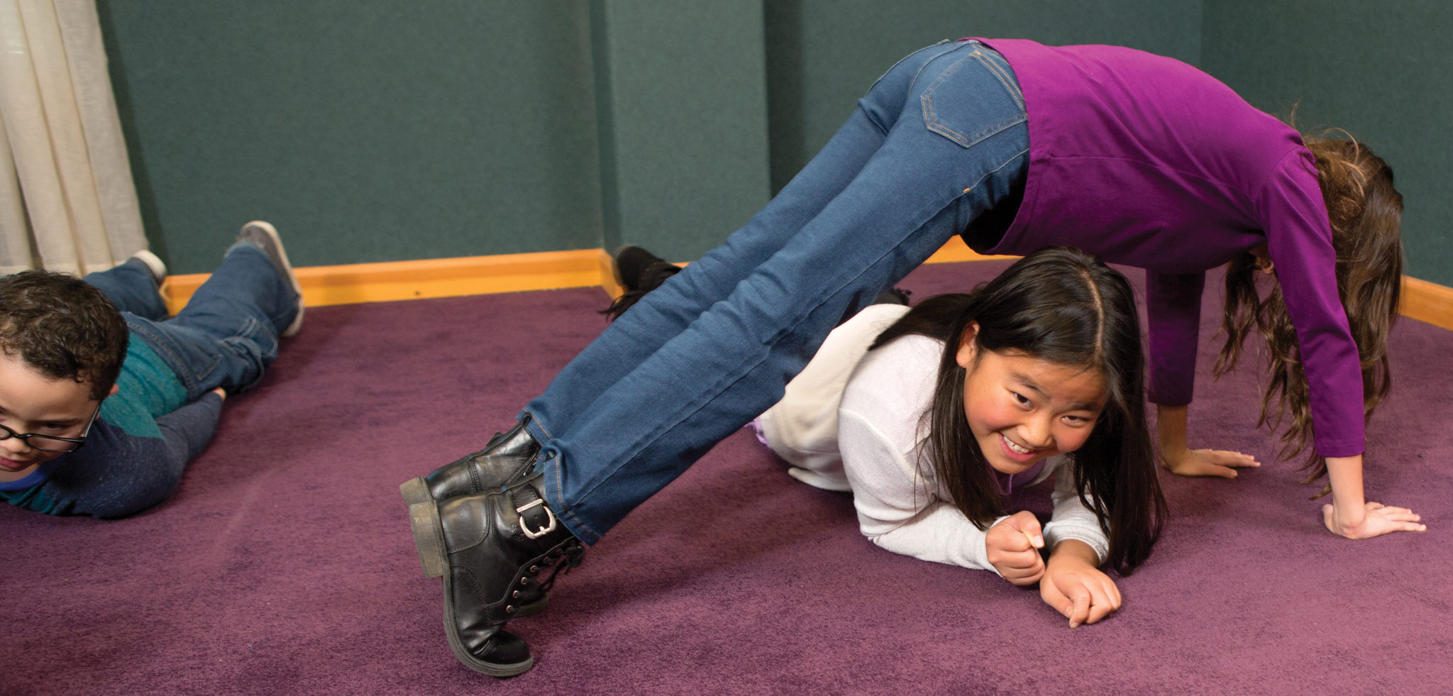 A girl crawls under another girl who is making a body out of body.