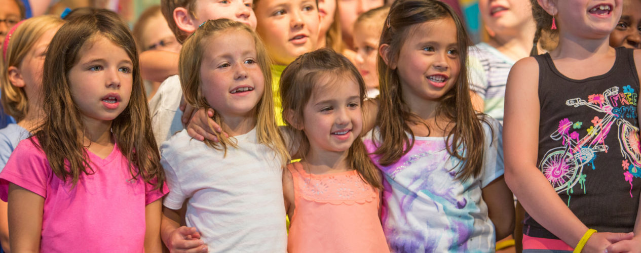 A group of preteen and elementary girls with their arms wrapped each other.