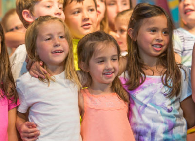 A group of preteen and elementary girls with their arms wrapped each other.