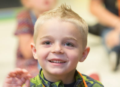 A preschool boy smiles during a Bible story.