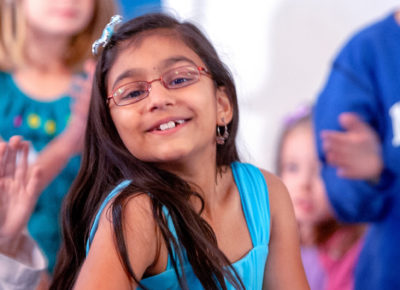 An older elementary girl smiles as she looks at the camera.