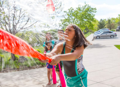A girl hitting a water balloon with a plastic bat. This is a summer outreach activity that can be used all year long.