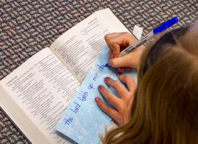A girl copies a Bible verse onto a sheet of paper during released time education.