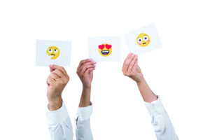 Three hands holding up three different emoji cards.