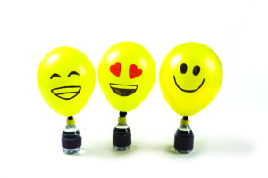 Three yellow balloons decorated to look like emojis.