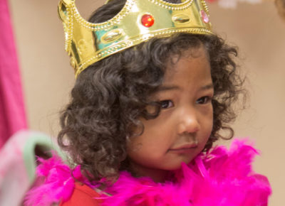 A little girl is dressed as a princess at a breakfast.
