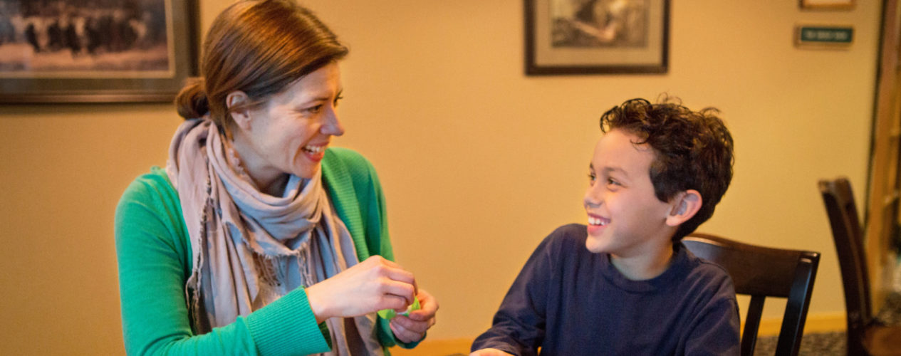 A woman volunteer helps an elementary-aged boy read his Easter egg prayers.