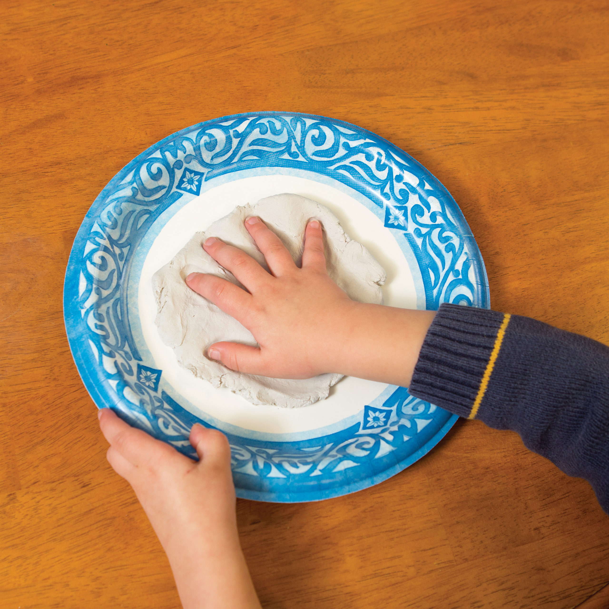 A child pushes his hand into a clay circle