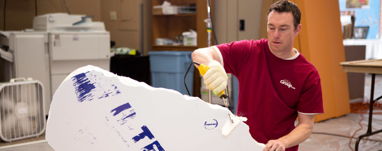 A male volunteer cuts styrofoam shapes.