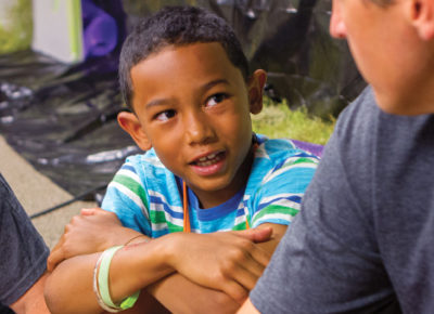 A male volunteer talks to a kid about forgiveness during a lesson.