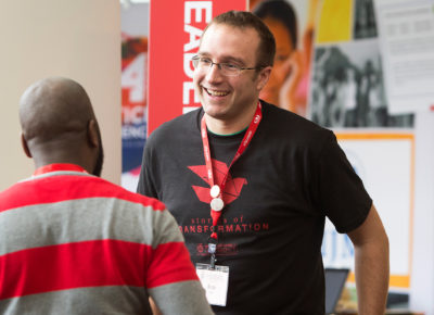 A children's ministry leader at a ministry fair talks to a volunteer.