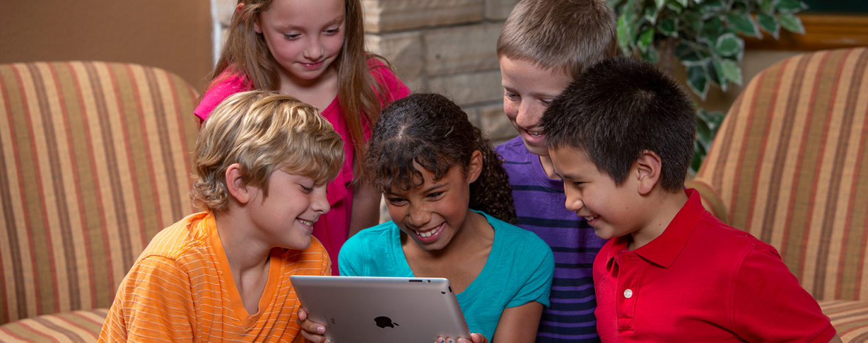 A group of preteens using an iPad during a technology-based lesson.