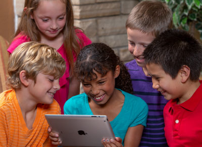 A group of preteens using an iPad during a technology-based lesson.