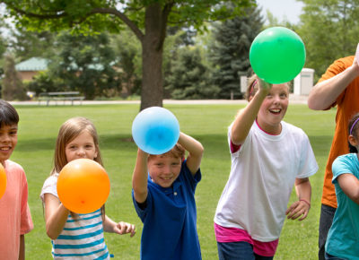 A group of children participating in a peer pressure activity involving balloons.