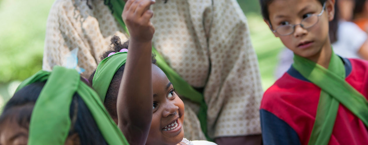 A little girl fundraising as she holds up a coin joyfully.