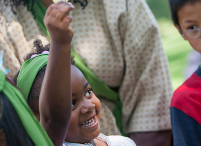 A little girl fundraising as she holds up a coin joyfully.